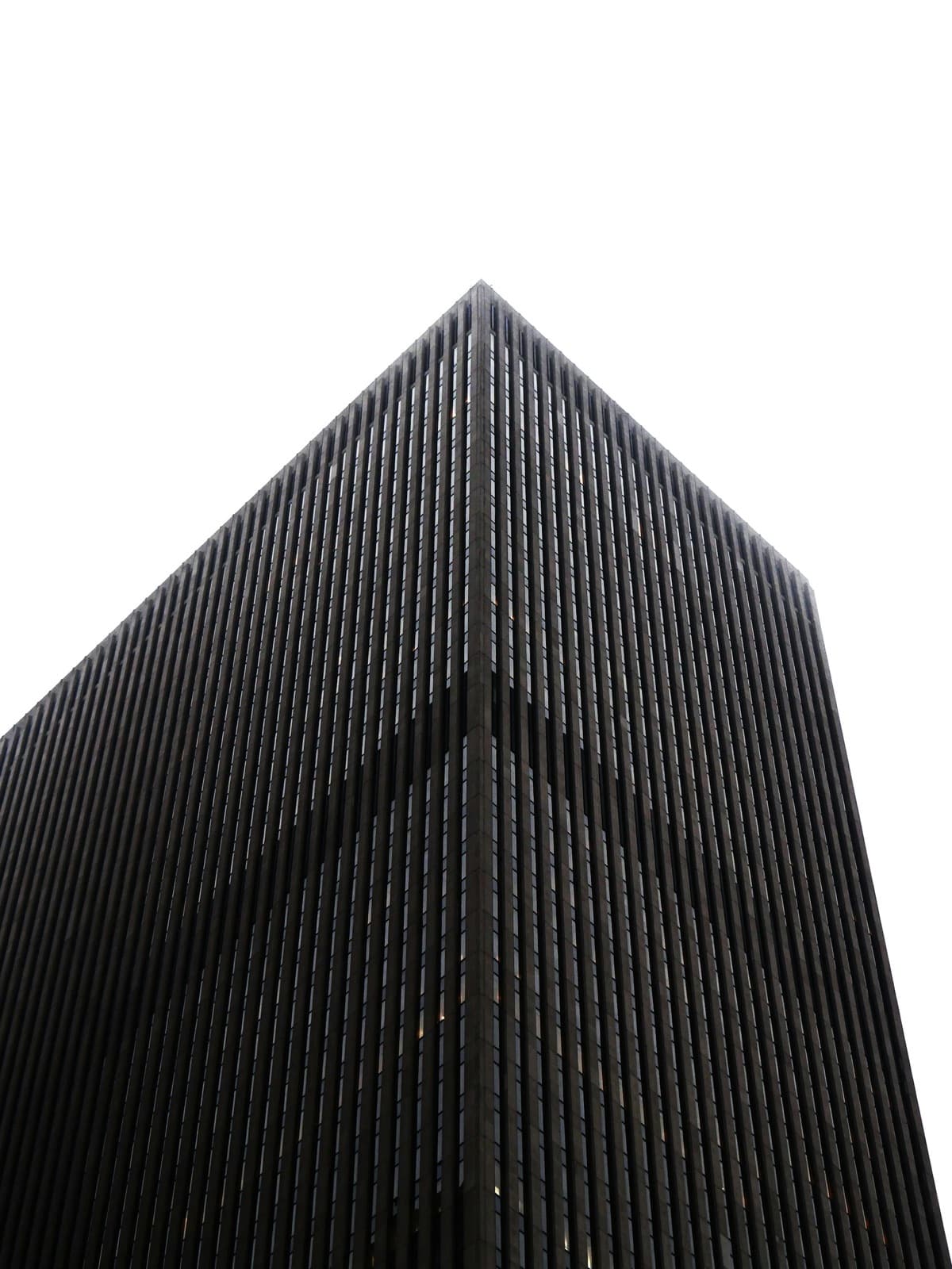 The corner of a high-scale black building with cloud white sky